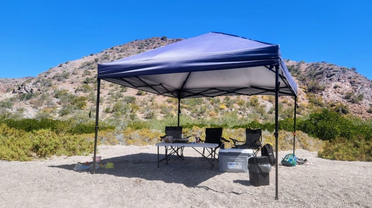 Carpa de sombra, sillas e hielera montadas en una playa de arena blanca de las islas de Loreto