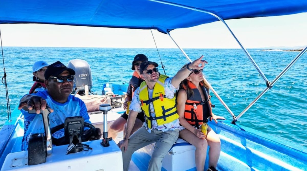 Pasajeros con chaleco salvavidas bajo el toldo de la panga Loreto Star, buscando ballenas en la Bahía de Loreto, Baja California Sur
