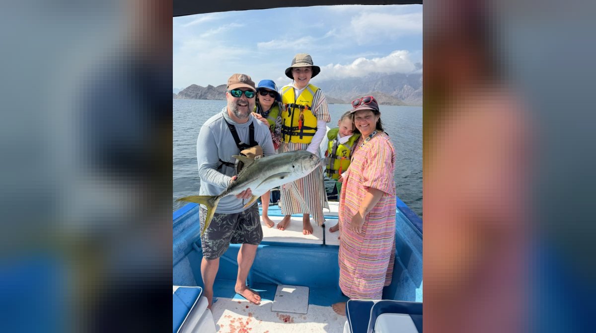 Familia con un jurel recién pescado a bordo de la panga Loreto Star frente a las islas de Loreto